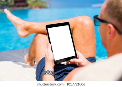 Man using tablet on vacation by the pool. Digital tablet mockup, vertical screen orientation.