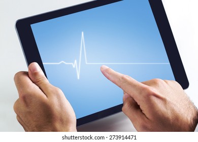 Man using tablet pc against medical background with blue ecg line