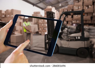 Man using tablet pc against warehouse worker loading up pallet - Powered by Shutterstock