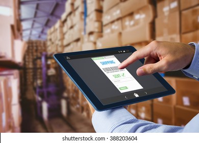 Man using tablet pc against forklift in large warehouse