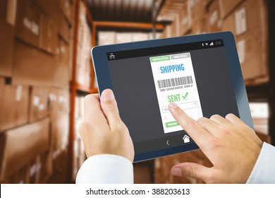 Man using tablet pc against shelves with boxes in warehouse