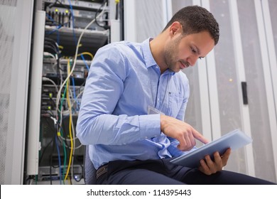 Man using tablet pc beside servers in data center