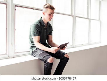 Man using tablet sit ont the window border