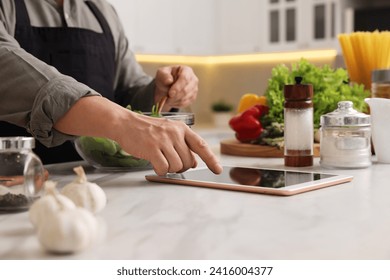 Man using tablet while cooking at countertop in kitchen, closeup
