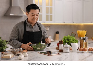 Man using tablet while cooking in kitchen