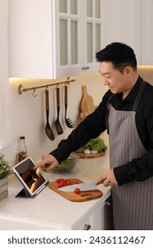 Man using tablet while cooking in kitchen