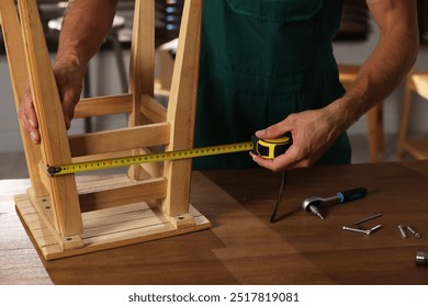 Man using tape measure while repairing wooden stool indoors, closeup - Powered by Shutterstock