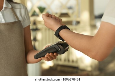 Man using terminal for contactless payment with smart watch in cafe, closeup - Powered by Shutterstock