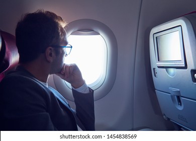 Man Using Touchscreen In Modern Airplane Seat.