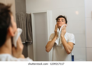 Man Using Towel To Dry His Face In Bathroom