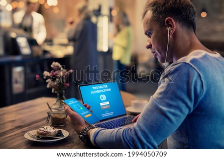 Man using two factor authentication on laptop computer and mobile phone