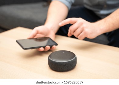 Man Using Virtual Assistant And Smart Speaker At Home