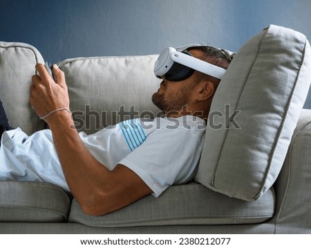 Man using virtual reality glasses, wearing new generation vr headset on sofa.