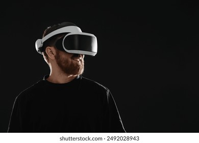 Man using virtual reality headset on black background. Space for text
