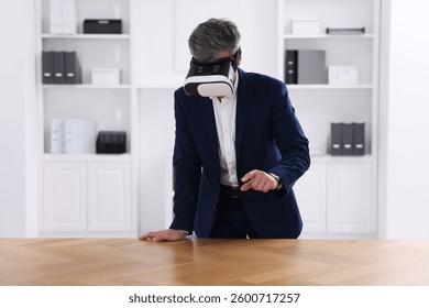 Man using virtual reality headset at desk in office