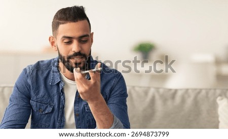 Man Using Voice Assistant on Smartphone in Modern Living Room Setting