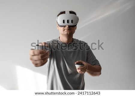 
A man is using a VRAR headset against a gray background. Strong emotions and impressions from using the VRAR headset.