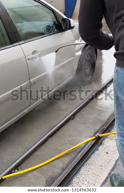 Man Using Water Pressure Machine to Wash a Car\
on Blurred Background