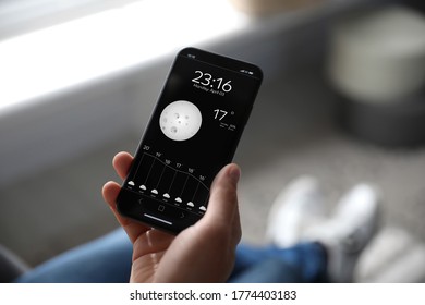 Man using weather forecast app on smartphone indoors, closeup