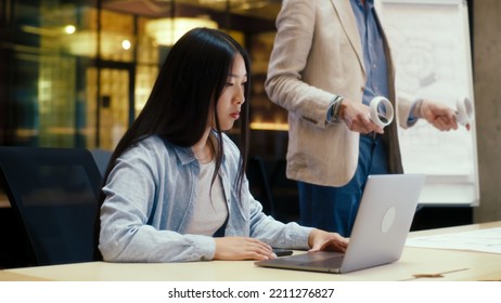 Man using wireless controllers, examining blueprint in virtual reality. Asian female engineer watching data on laptop. Work in modern office of engineering company. Cyberspace digital technology