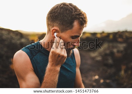 Man using wireless earphones air pods on running outdoors. Active lifestyle concept.