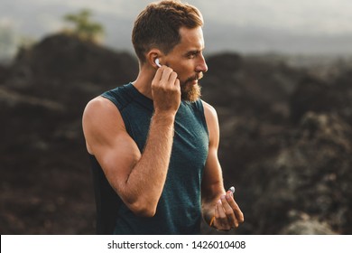 Man using wireless earphones on running outdoors. Active lifestyle concept.