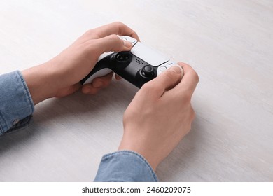 Man using wireless game controller at white table, closeup