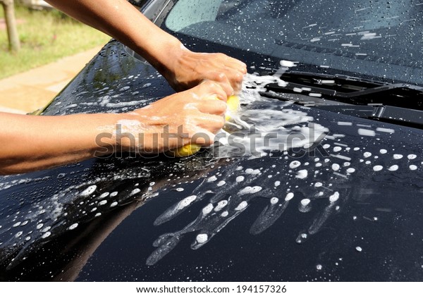the man using\
yellow sponge to wash his\
car
