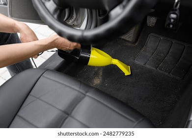 Man vacuums dirty car floor using portable vacuum cleaner. Maintaining order in car interior.  - Powered by Shutterstock