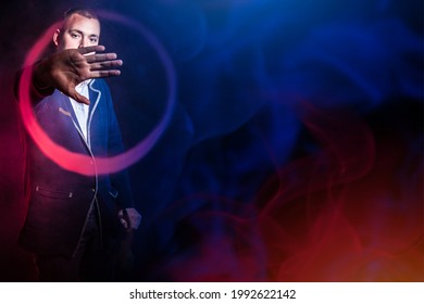 Man with vape mod. Vaper smoking e-cigarette to quit tobacco. Vaper makes a ring of smoke. Young man is engaged in vape. Man with a vape device on a dark background. Smoke from e-cig in neon light - Powered by Shutterstock