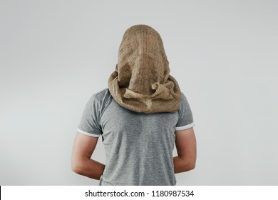 Man with veiled face on a light background. The concept of kidnapping, detention, and crime. No face. The man has a cloth bag on his head. Kidnapping by terrorists.