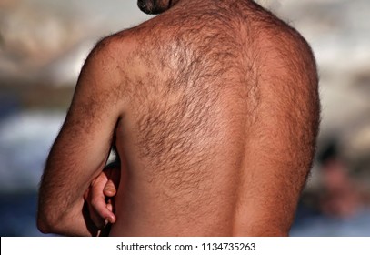 Man With A Very Hairy Back Standing Outside By A River On A Hot Summer Day