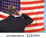 A man in a VFW cap saluting an old faded 48 star American flag.