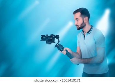 Man videographer. Guy with camera is making video. Operator uses camera with stabilizer. Man videographer on blue. Shooting movie. Young videographer at work. Persona video director.