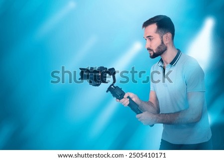 Man videographer. Guy with camera is making video. Operator uses camera with stabilizer. Man videographer on blue. Shooting movie. Young videographer at work. Persona video director.
