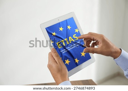 Man viewing ETIAS webpage using tablet computer indoors, closeup. European Travel Information and Authorisation System