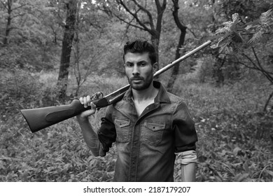 A Man With Vintage Shotgun In The Forest In Black And White