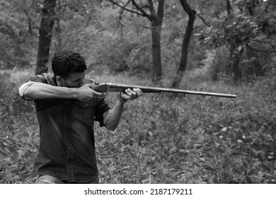 A Man With Vintage Shotgun In The Forest In Black And White