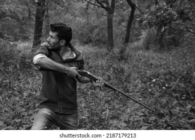 A Man With Vintage Shotgun In The Forest In Black And White