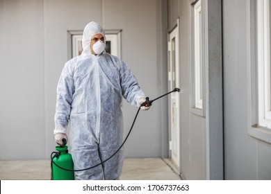 Man in virus protective suit and mask disinfecting buildings of coronavirus with the sprayer. Infection prevention and control of epidemic. World pandemic. - Shutterstock ID 1706737663