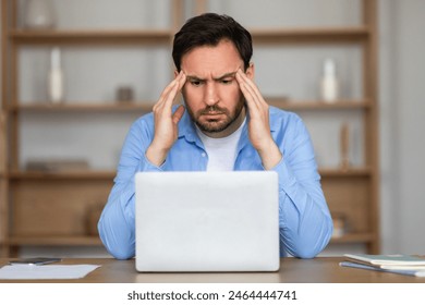 A man is visibly stressed as he sits at a desk with his head in his hands. He appears deep in thought, possibly facing a challenging situation or problem. - Powered by Shutterstock