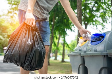 A man volunteers collecting garbage in public park and he dump the bottle to the recycle bin.Environmental protection Concept.