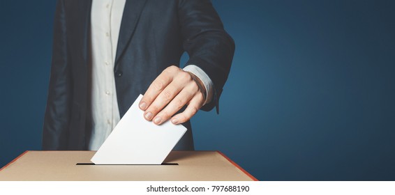 Man Voter Putting Ballot Into Voting box. Democracy Freedom Concept Near Blue Wall Copy-Space - Shutterstock ID 797688190