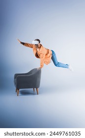 A man in a VR headset performs a gravity-defying trick on a chair in a futuristic studio setting.