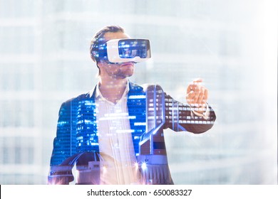 Man in VR headset working in augmented reality. Guy using virtual reality glasses to interact with cyberspace objects. Immersion in virtual world mixed media exposure concept, illuminated night city - Powered by Shutterstock