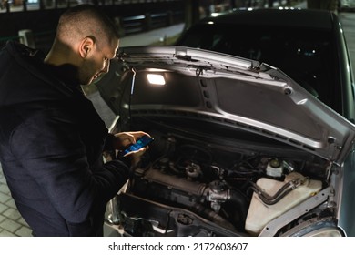 A man is waiting for a car service at night alone  on the road with a broken car - Powered by Shutterstock