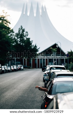 Man is waiting in the car while his hand with the watch and lit cigarette is hanging outside the car