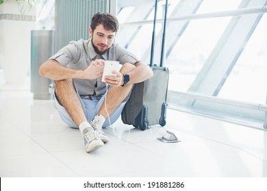 Man Waiting For His Flight In The International Airport And Typing Message On Phone