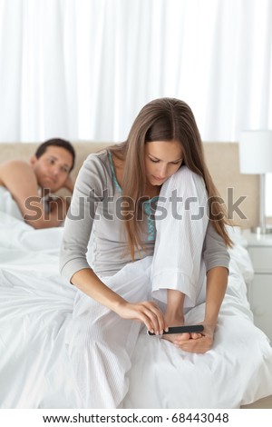 Man waiting for his girlfriend filing her toenails on the bed at home
