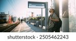 A man is waiting for a train on the platform. A young guy, a passenger with a backpack is standing on the platform waiting for the train